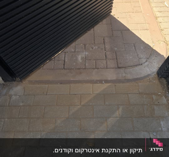 שער מתכת פתוח על שביל מרוצף בלבנים